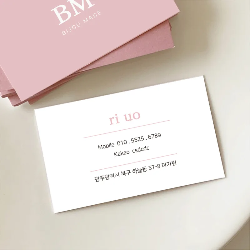 분홍 명함 더미 위에 흰 명함 한 장을 얹은 사진