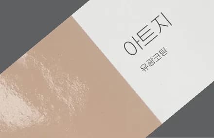 '아트지 유광코팅' 표기가 적힌 표면에 빛이 번쩍이는 베이지색 스티커 용지 견본